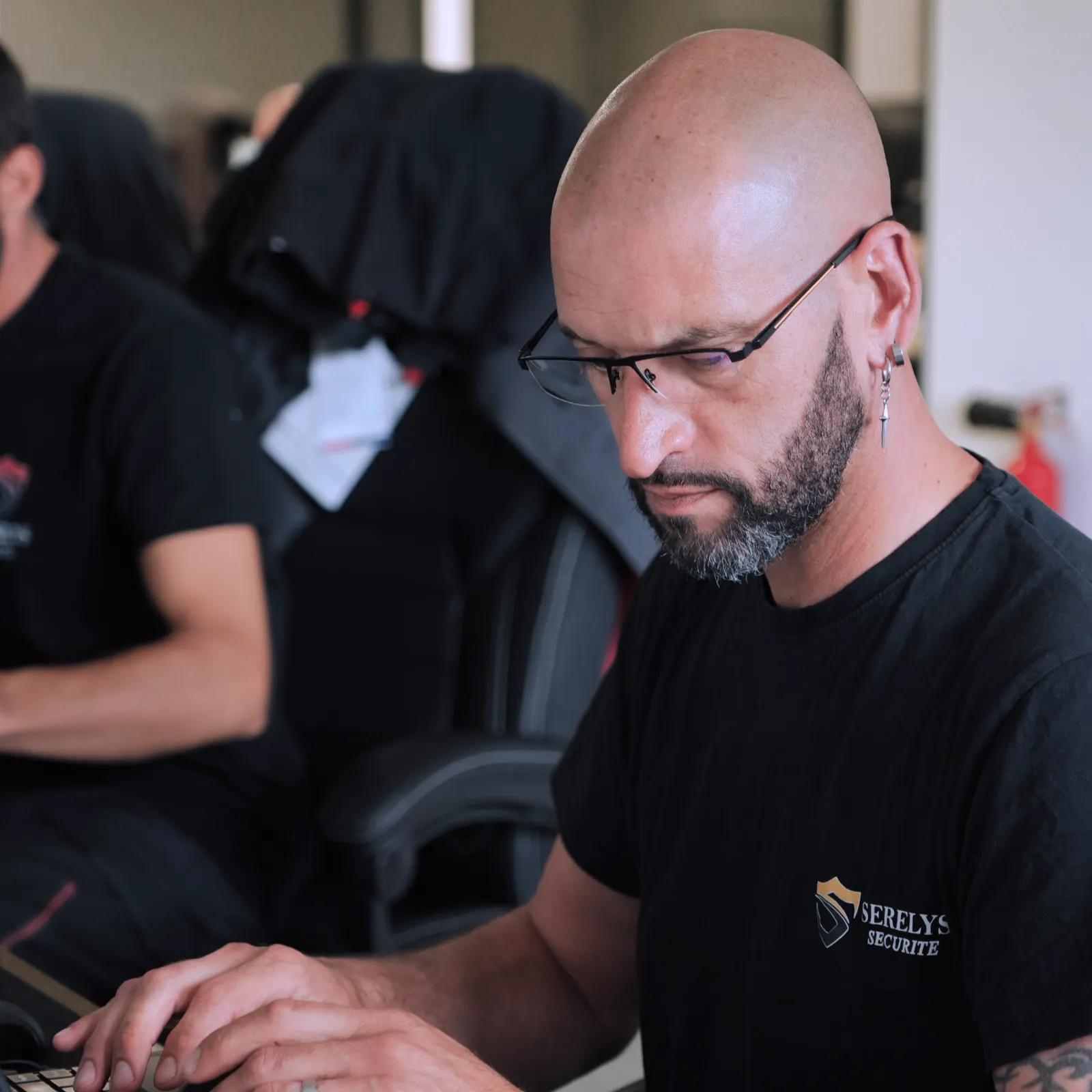 Technicien SERELYS SÉCURITÉ en Vendée configurant une solution de vidéosurveillance sur ordinateur, porteur de lunettes et polo professionnel