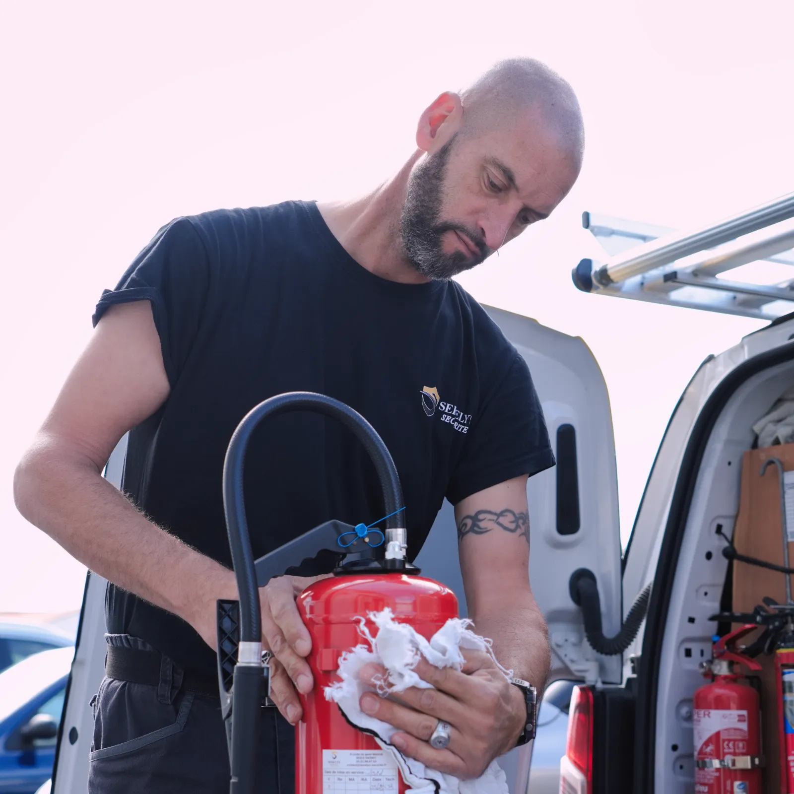 Technicien SERELYS SÉCURITÉ en Vendée effectuant la maintenance d'un extincteur rouge, démontrant l'expertise en solutions de sécurité incendie