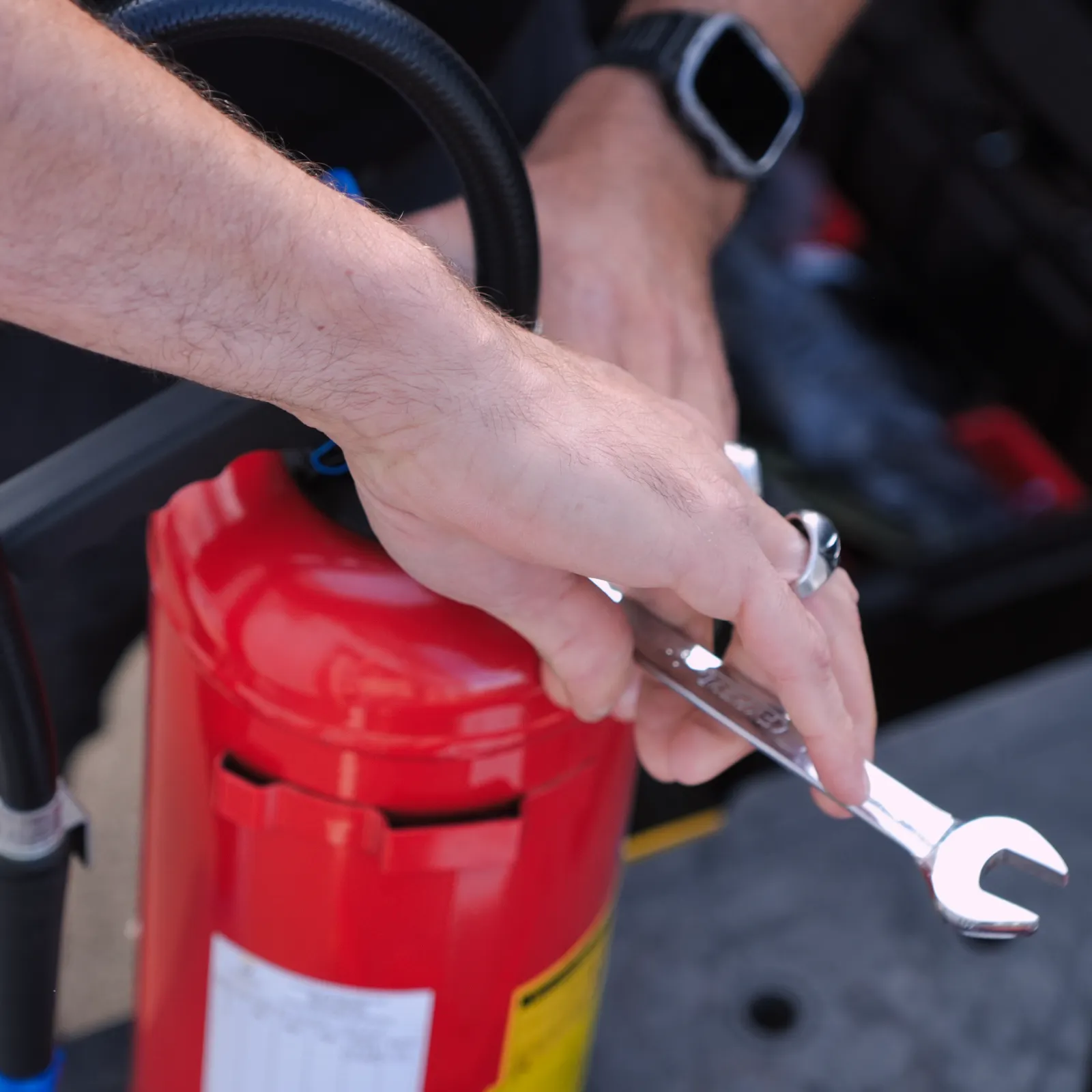 Technicien SERELYS SÉCURITÉ en Vendée effectuant la maintenance d'un équipement de sécurité incendie rouge avec outil de précision