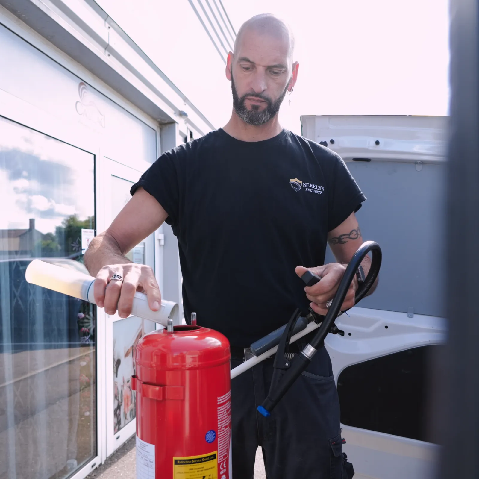 Technicien SERELYS SÉCURITÉ en Vendée inspectant un extincteur rouge lors d'une intervention de maintenance de sécurité