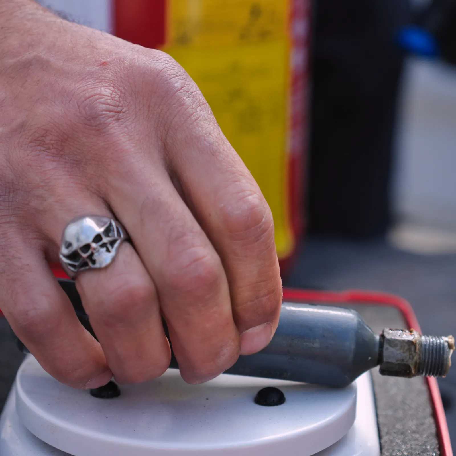 Technicien SERELYS SÉCURITÉ en Vendée installant un système de vidéosurveillance, portant une bague tête de mort, manipulant un connecteur de caméra de sécurité professionnelle