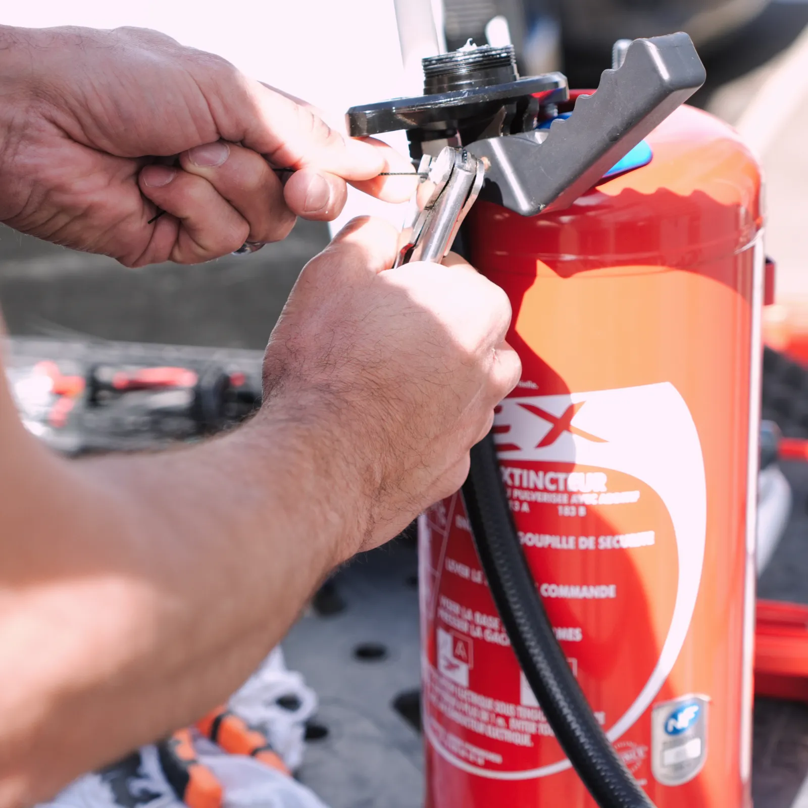 Technicien de SERELYS SÉCURITÉ en Vendée manipulant le système de déclenchement d'un extincteur, démontrant les procédures de sécurité et de prévention des risques incendie