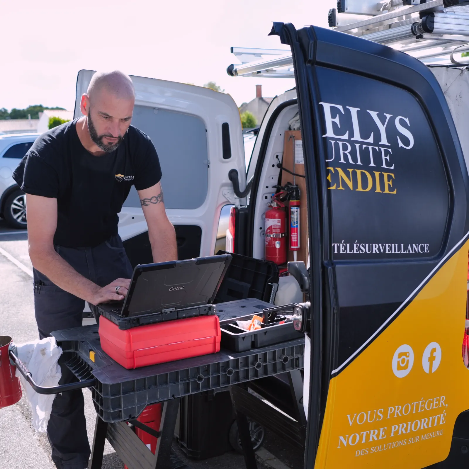Technicien SERELYS SÉCURITÉ en Vendée installant un système de vidéosurveillance, utilisant un ordinateur portable et des outils de diagnostic dans un véhicule d'intervention
