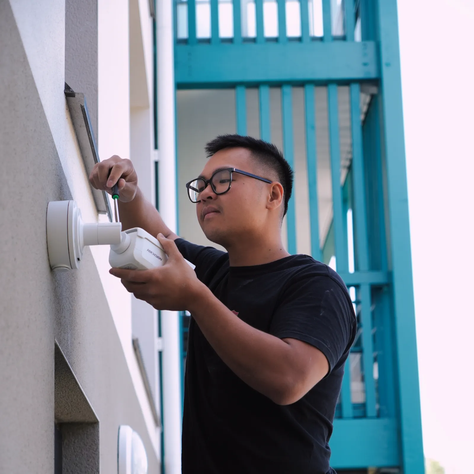 Technicien SERELYS SÉCURITÉ en Vendée installant une caméra de vidéosurveillance professionnelle sur la façade d'un bâtiment, démontrant l'expertise en solutions de sécurité