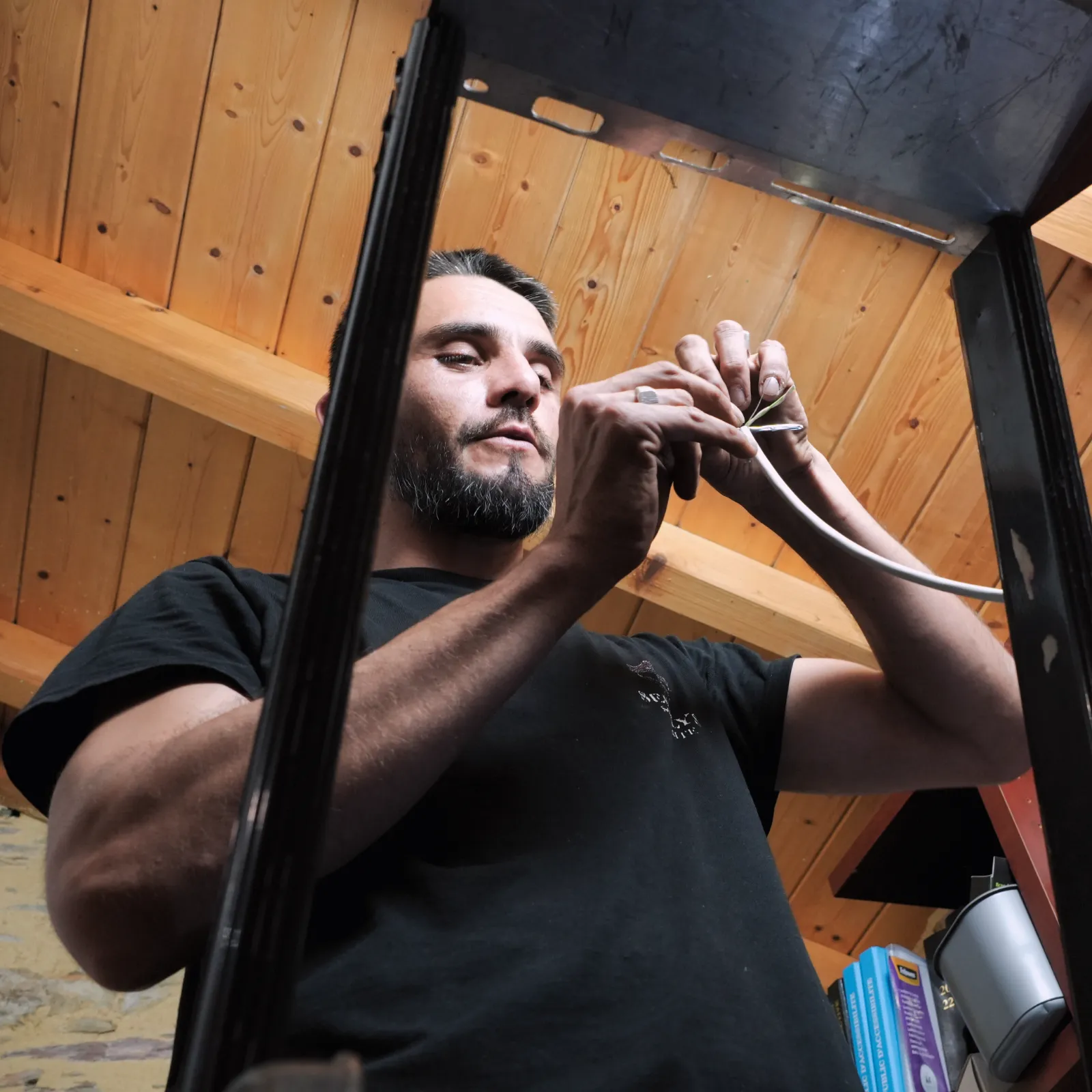 Technicien SERELYS SÉCURITÉ en Vendée installant un câble de vidéosurveillance sous plafond en bois, démontrant l'expertise en solutions de sécurité