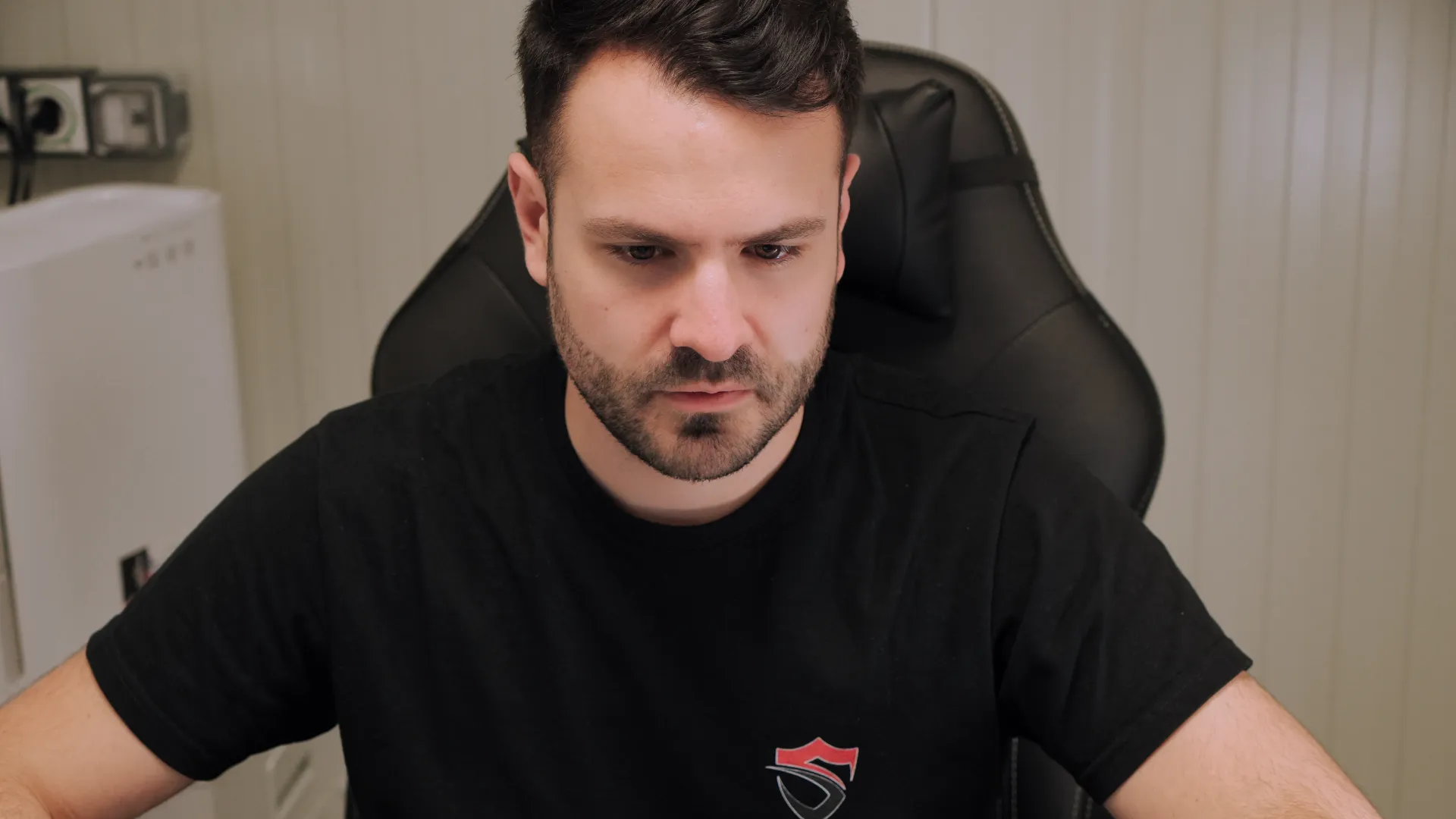Technicien SERELYS SÉCURITÉ en Vendée analysant un système de vidéosurveillance, portant un t-shirt noir avec logo professionnel, concentré sur son écran de monitoring