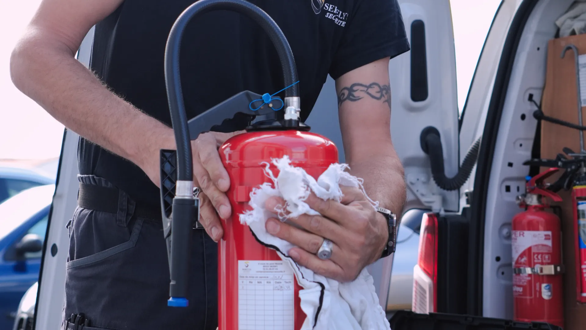 Technicien SERELYS SÉCURITÉ en Vendée inspectant un extincteur rouge lors d'une intervention de maintenance de sécurité incendie