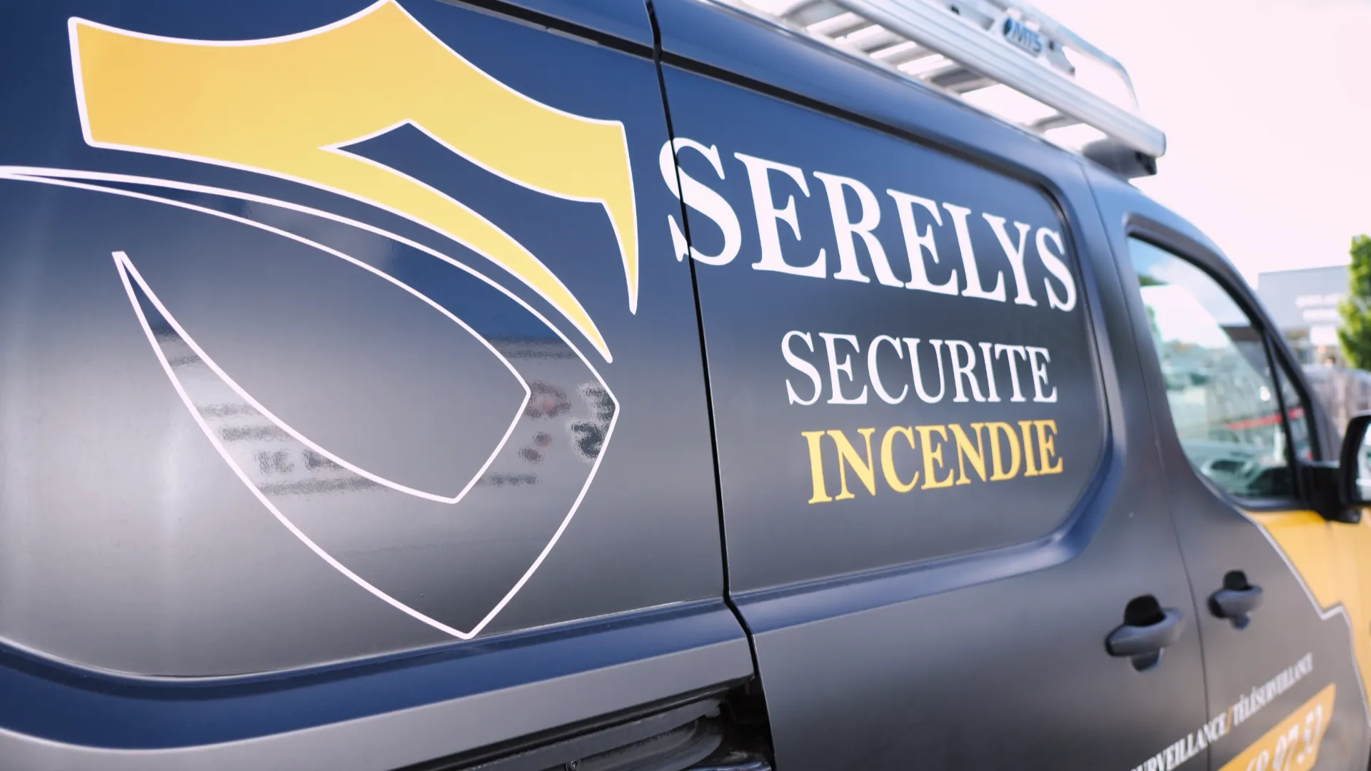 Véhicule de intervention SERELYS SÉCURITÉ en Vendée avec logo bouclier jaune et bleu, spécialisé en vidéosurveillance et solutions de sécurité incendie