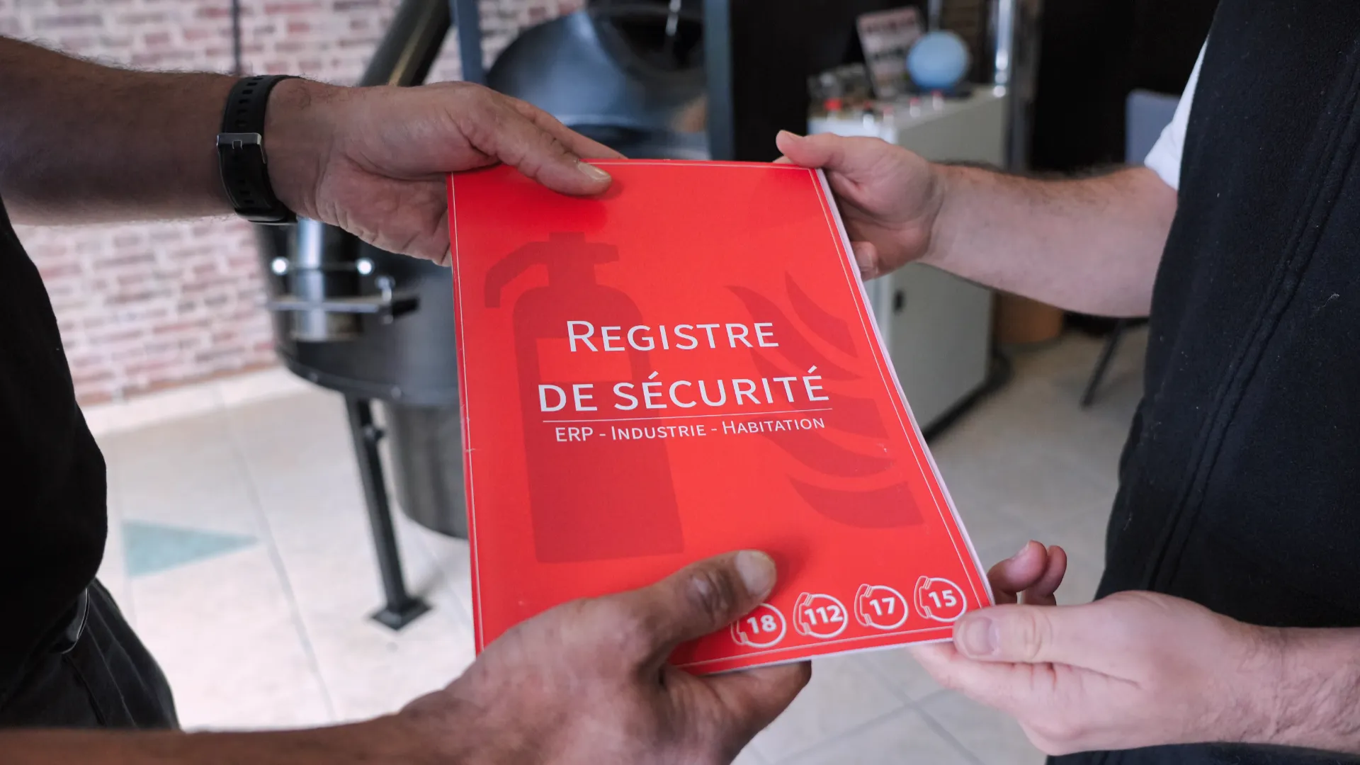 Remise d'un registre de sécurité rouge par SERELYS SÉCURITÉ en Vendée, document ERP Industrie Habitation pour la conformité réglementaire