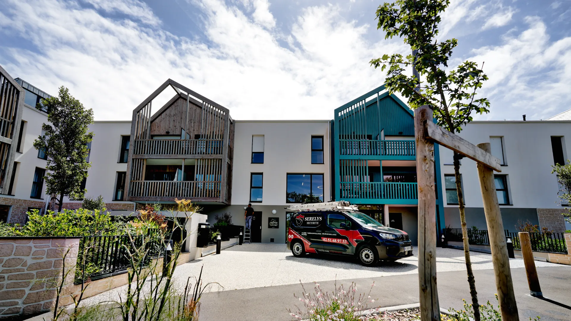 Siège social de SERELYS SÉCURITÉ en Vendée : bâtiment moderne blanc avec bardages turquoise et gris, véhicule de service de vidéosurveillance en cour