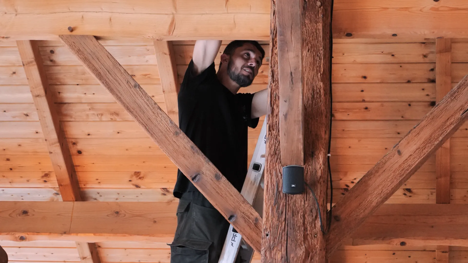 Technicien SERELYS SÉCURITÉ en Vendée installant une caméra de vidéosurveillance dans une structure en bois, démontrant expertise en solutions de sécurité