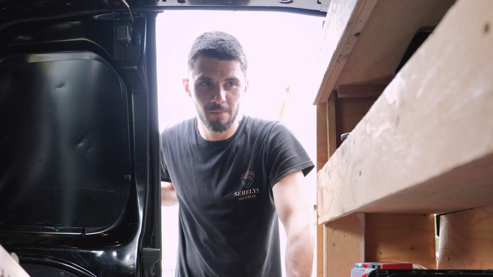 Technicien SERELYS SÉCURITÉ en Vendée inspectant l'intérieur d'un véhicule de service équipé pour la vidéosurveillance et solutions de sécurité