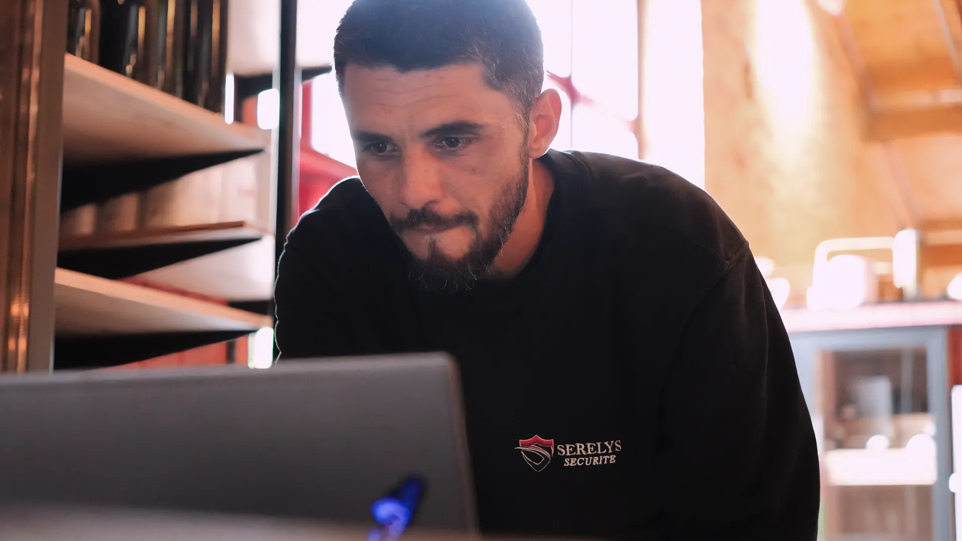 Technicien SERELYS SÉCURITÉ en Vendée consultant un écran de monitoring pour la vidéosurveillance, portant un polo noir de l'entreprise