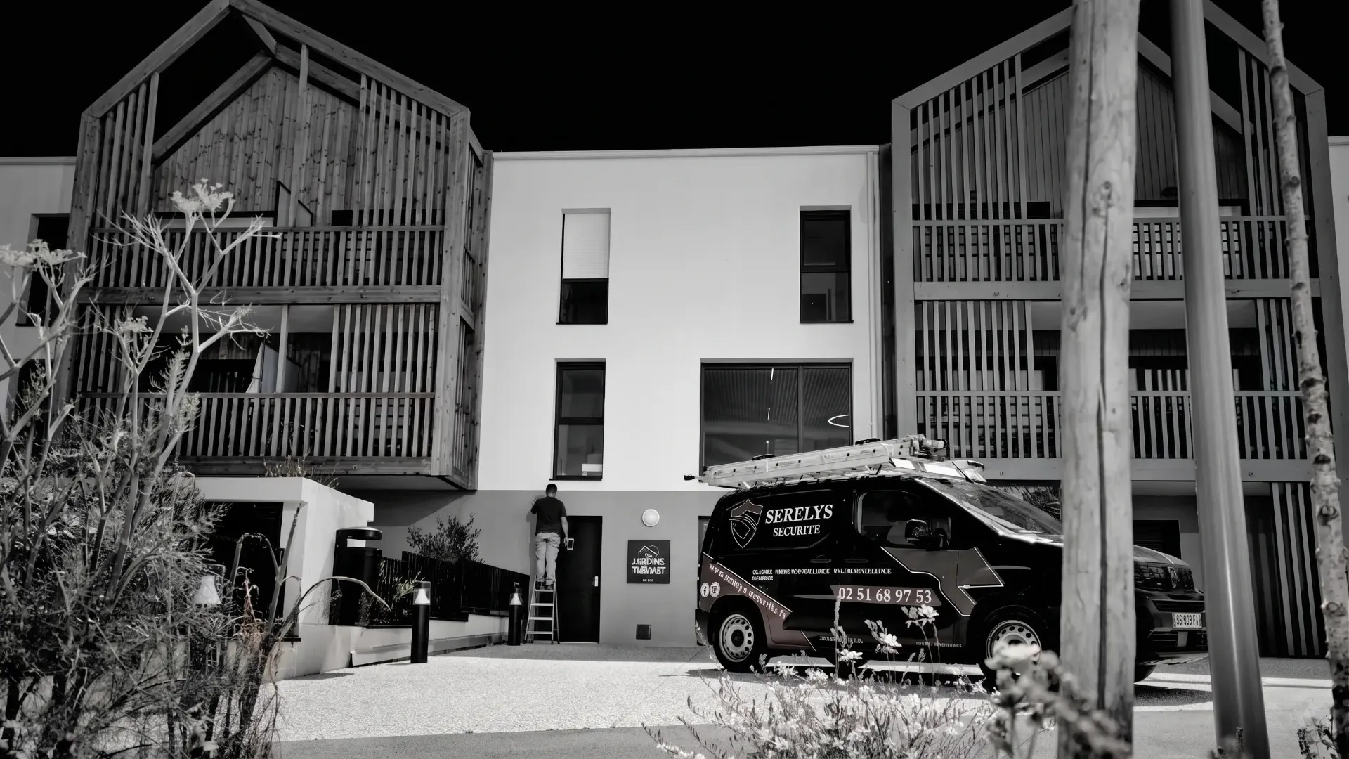 Siège social de SERELYS SÉCURITÉ en Vendée : bâtiment moderne avec façade blanche, portails métalliques sécurisés et véhicule de patrouille de vidéosurveillance