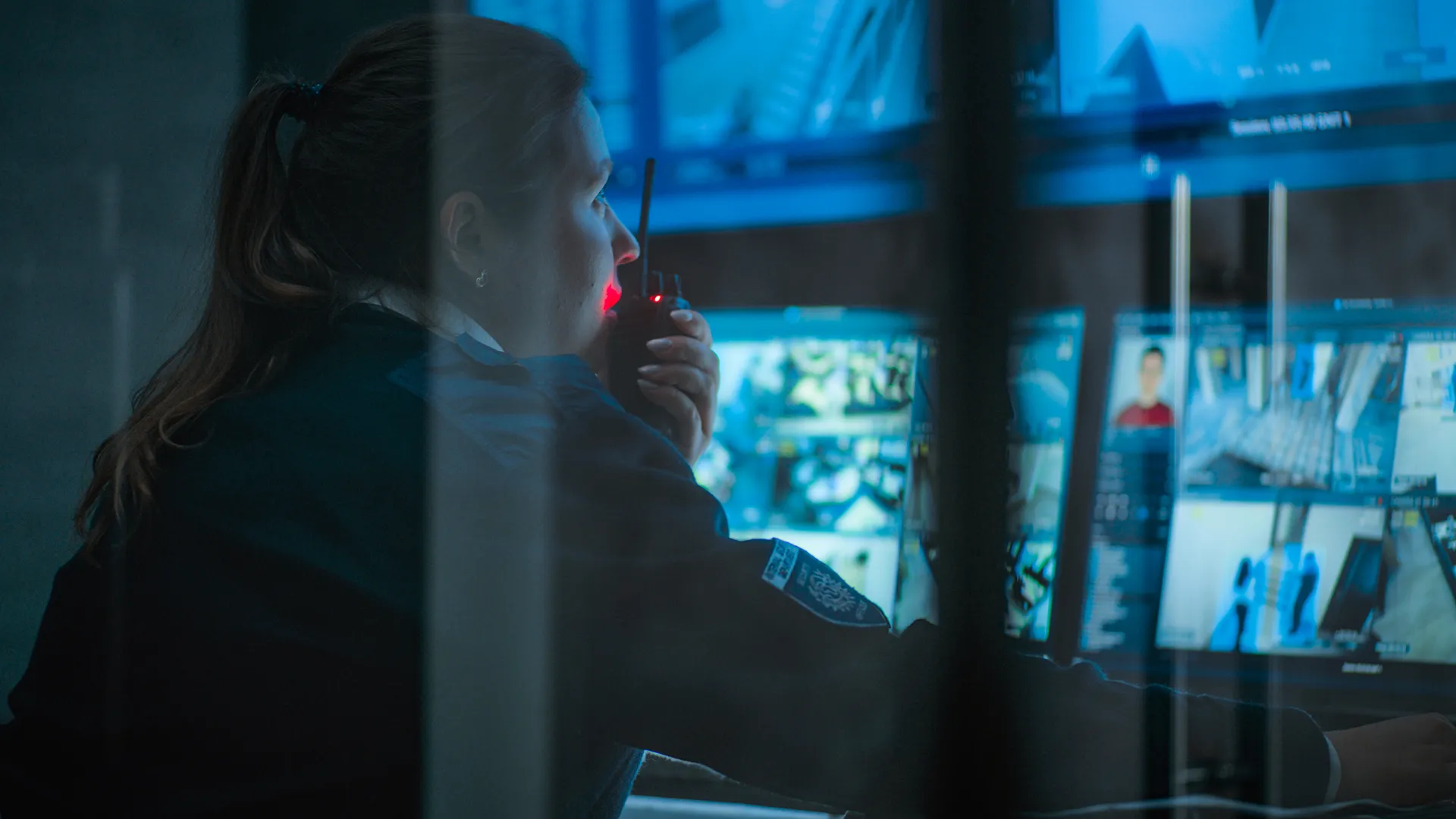 Agent de sécurité SERELYS SÉCURITÉ en Vendée utilisant une radio pour surveiller les écrans de vidéosurveillance en salle de contrôle