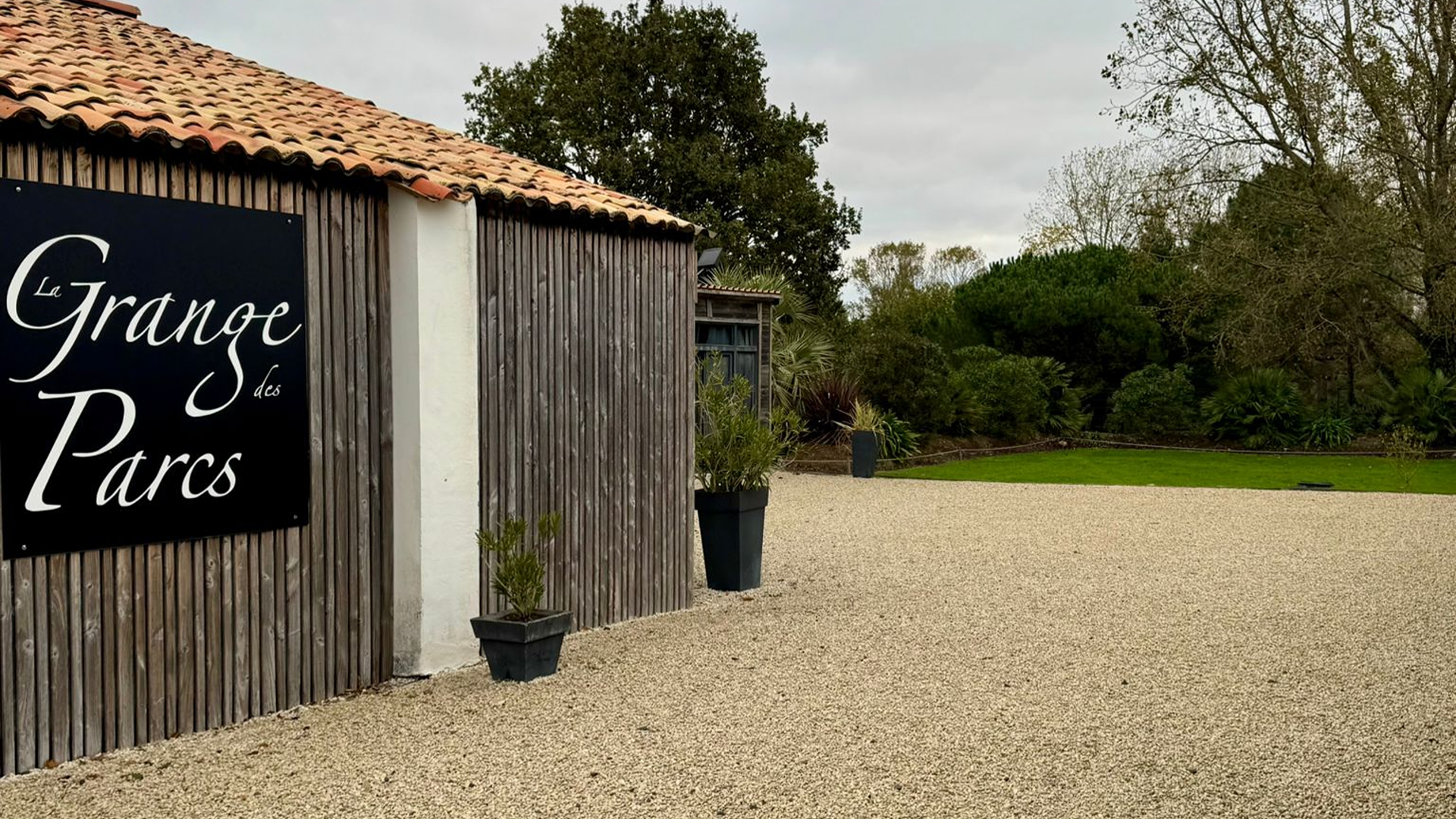 Entrée sécurisée de La Grange des Parcs en Vendée avec signalisation professionnelle, allée gravillonnée et bâtiments aux toitures typiques - Solutions de vidéosurveillance SERELYS SÉCURITÉ