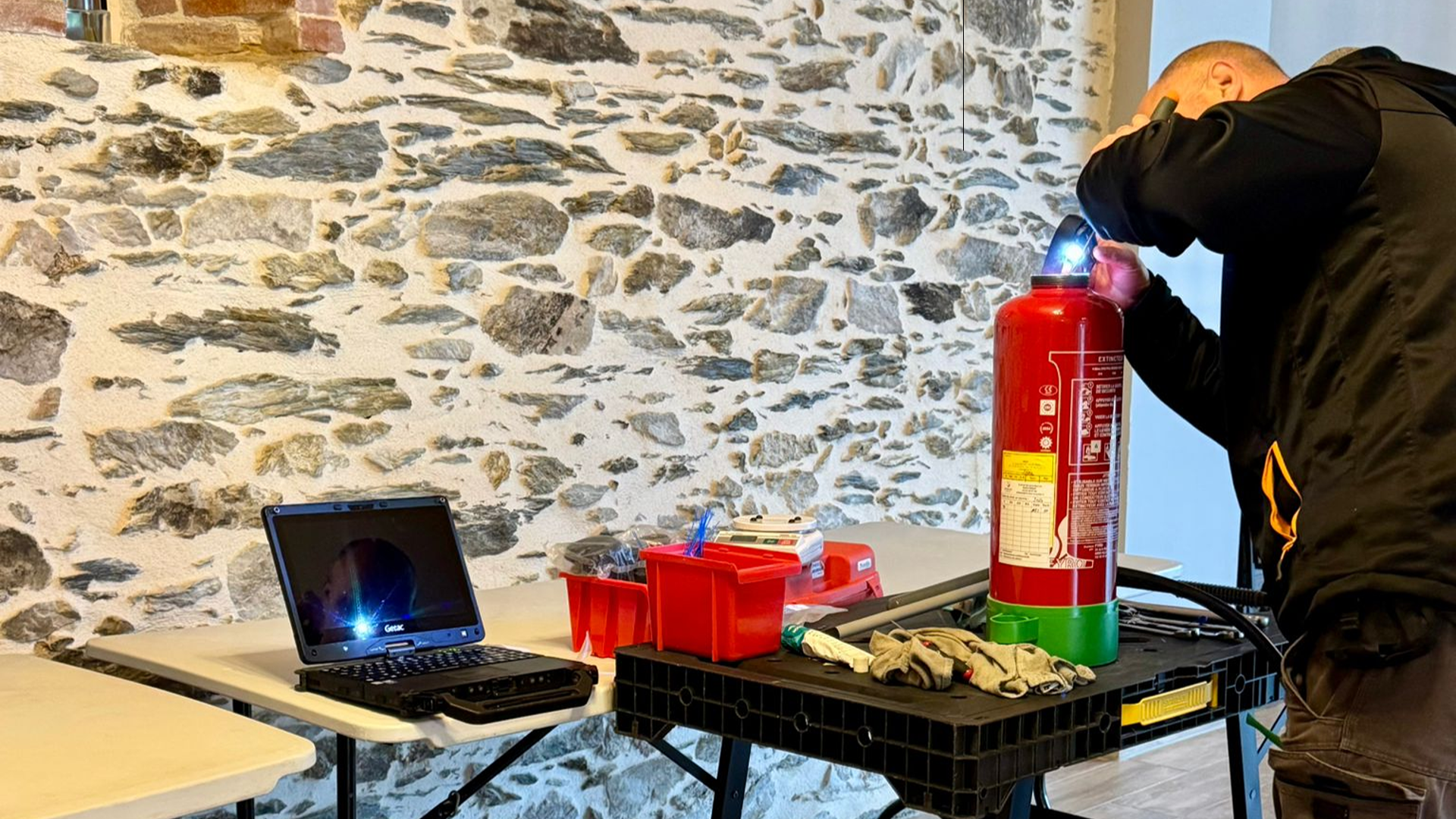 Démonstration de sécurité incendie par SERELYS SÉCURITÉ en Vendée : extincteur, équipements de protection et ordinateur portable sur table