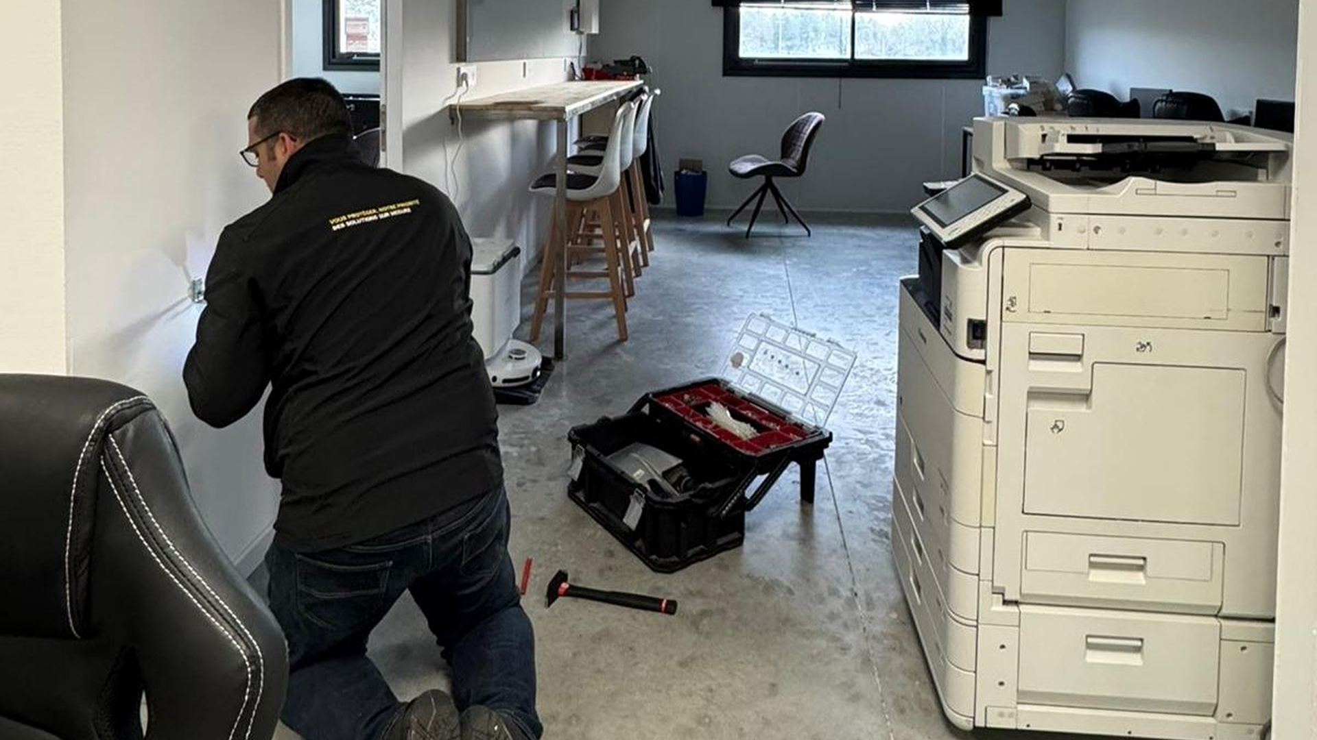 Technicien SERELYS SÉCURITÉ en intervention d'installation de vidéosurveillance en Vendée, dans un bureau avec équipements de sécurité et photocopieur professionnel