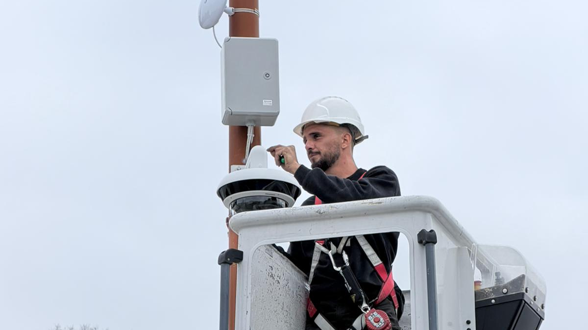 Technicien SERELYS SÉCURITÉ en Vendée installant une caméra de vidéosurveillance sur mât, équipé d'un casque de sécurité et harnais